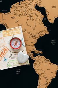 Flat lay photo of a map, passport, and compass, symbolizing travel and adventure.